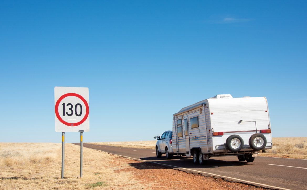 Road,Showing,130kms/hr,Sign,While,Car,With,Caravan,Drives,By.